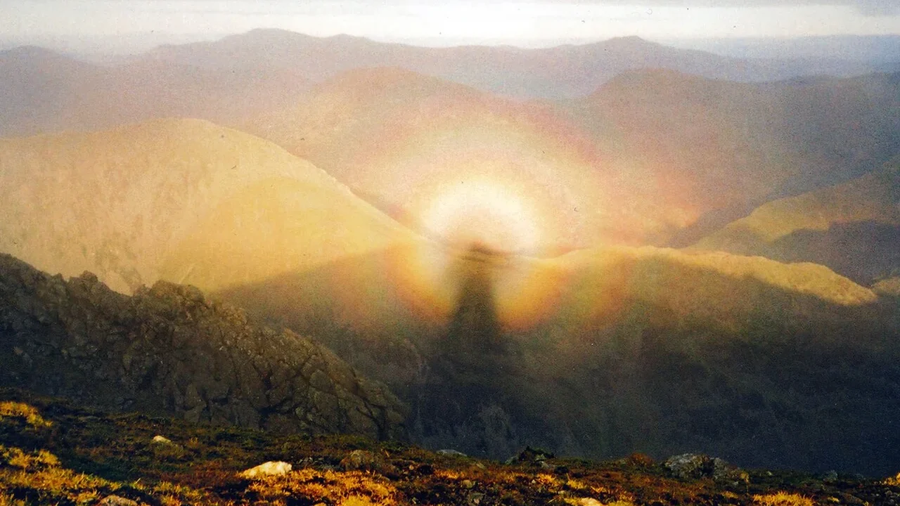 A human shadow surrounded by a colored glory on mountain cloud.