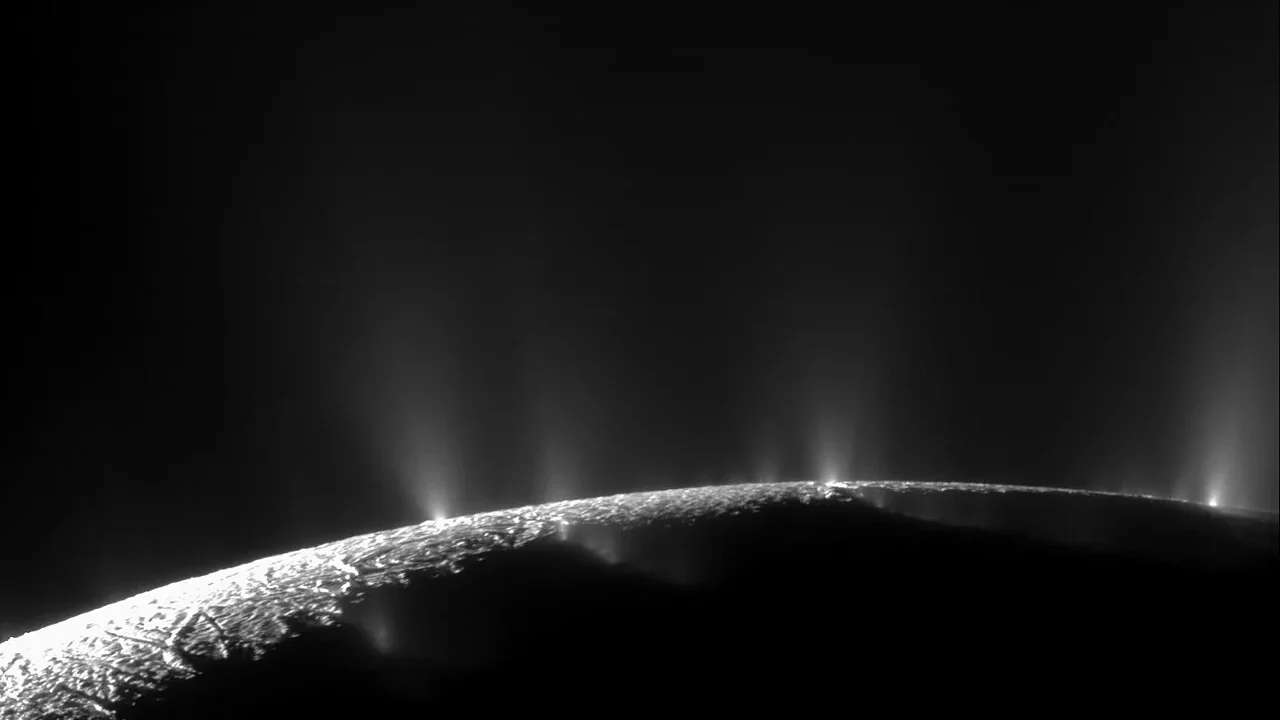 Cassini view of bright ice plumes rising from Enceladus against dark space.