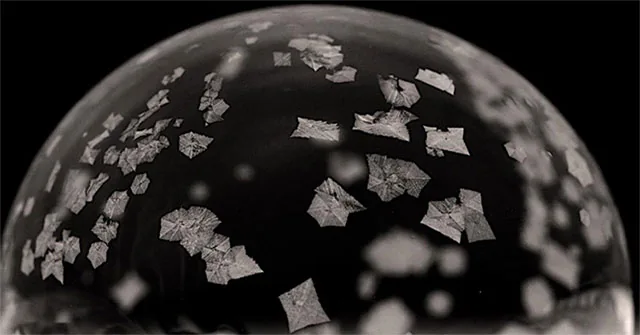 Ice crystals spreading across the surface of a soap bubble
